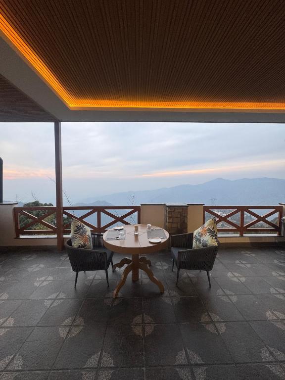 a table and chairs in a room with a view at Divine OAK Stay in Narendranagar