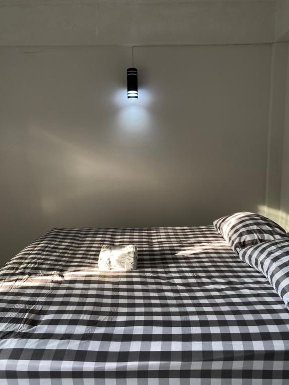 a bed with a black and white checkered sheets at Only fan guesthouse in Chumphon