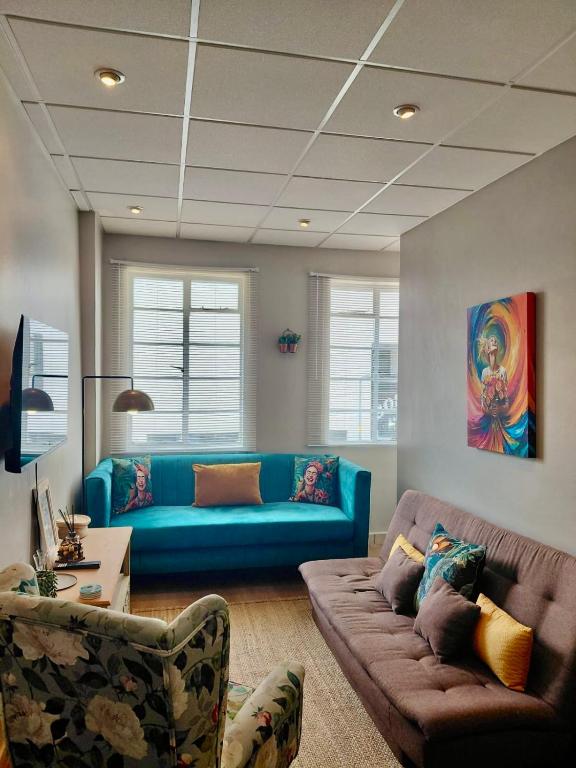 a living room with a blue couch and chairs at Melk Tert - Paarl - Self Catering Apartment in Paarl