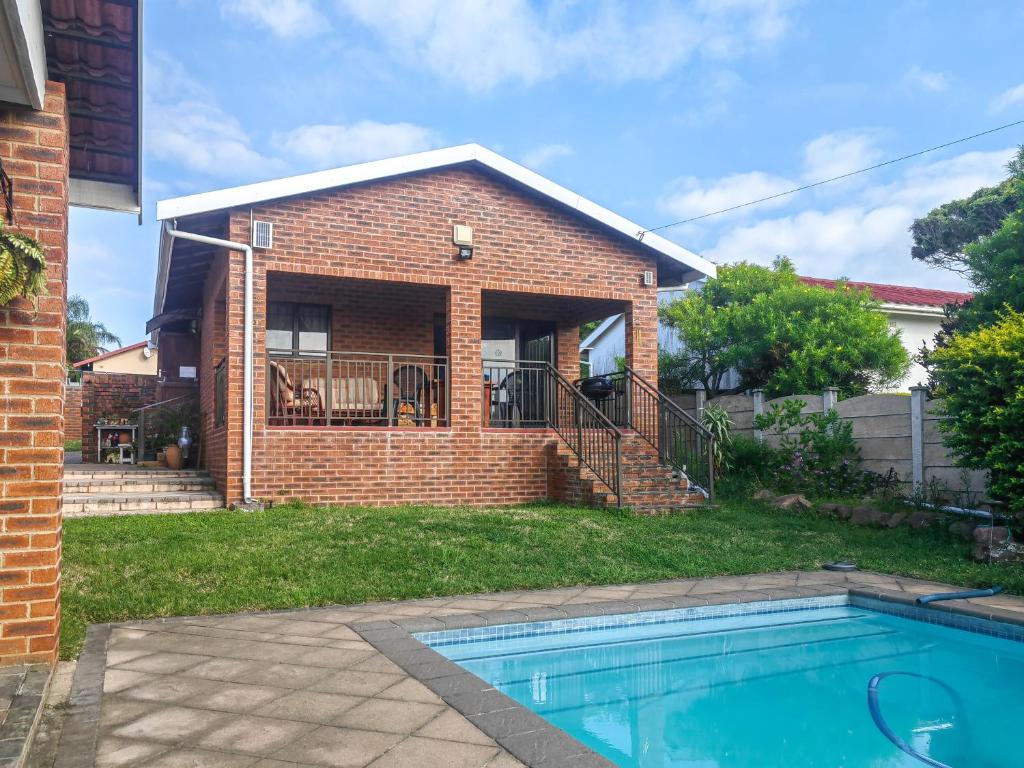 a brick house with a swimming pool in the yard at Swallows Rest Cottage KZN in Scottburgh