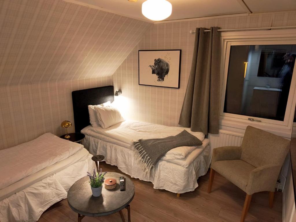 a hotel room with two beds and a chair at Hotell Trasten Tylösand in Tylösand