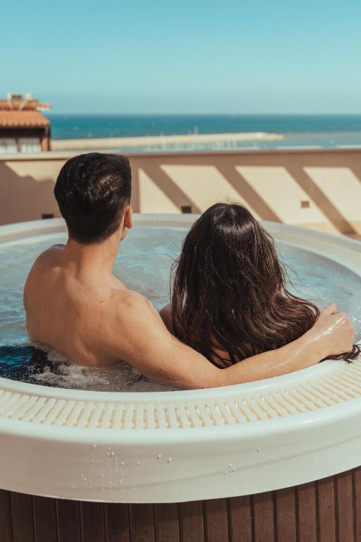 a man and a woman sitting in a hot tub at La Piazzetta Sea Rooms in Balestrate