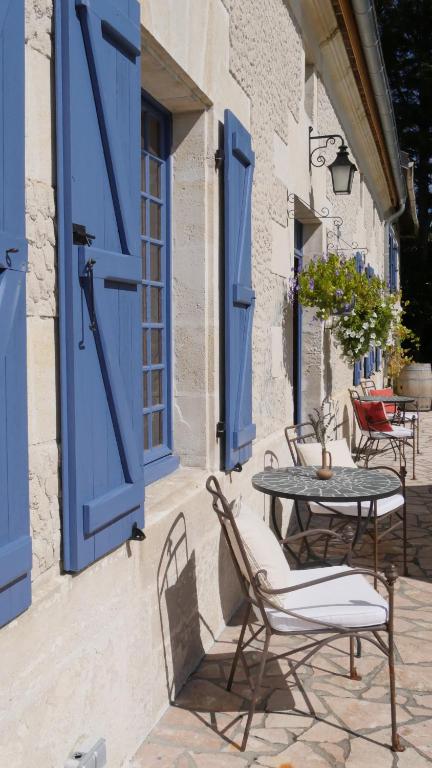 a patio with blue doors and tables and chairs at LE petit CHABO in Saint-Maigrin
