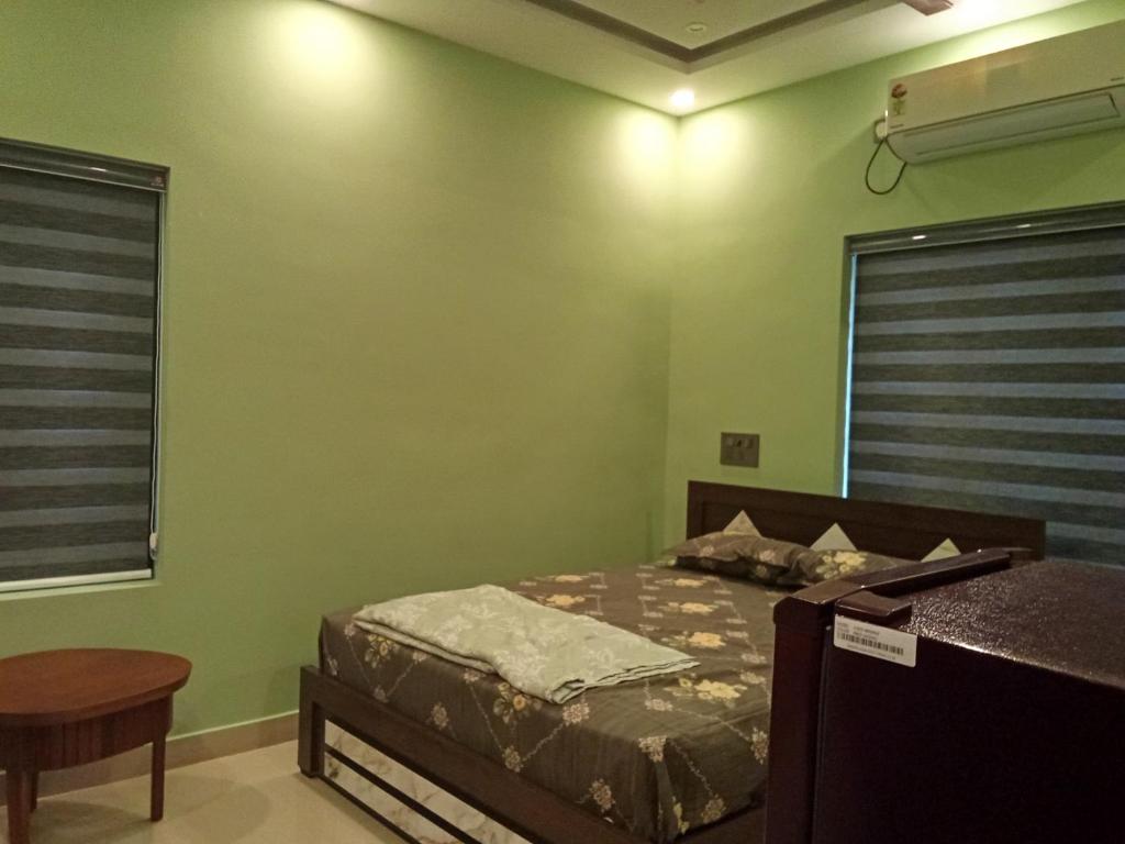 a bedroom with a bed and green walls at SBJ Road House in Varkala