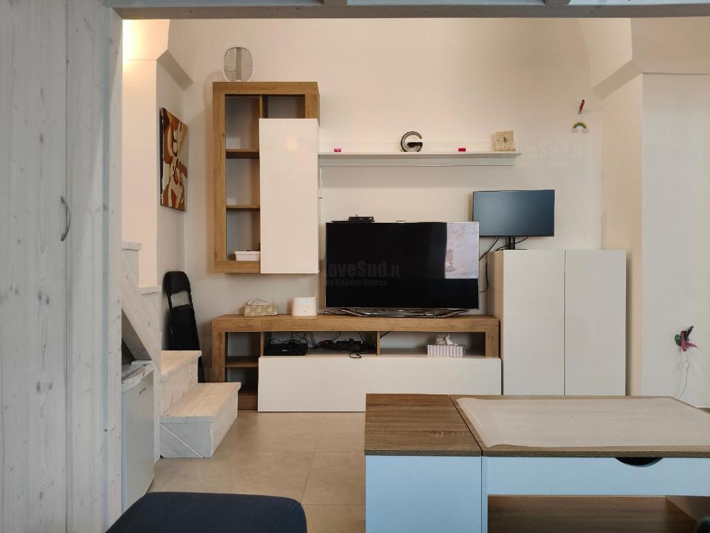 a living room with white cabinets and a television at La casa della nonna by LoveSud in Castrignano del Capo