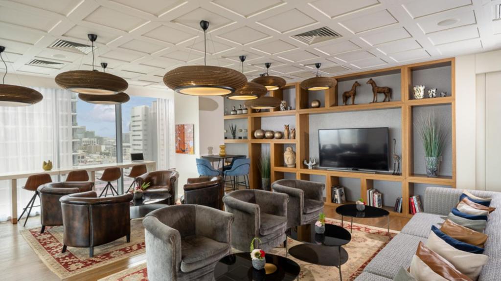 a living room with a bunch of chairs and a tv at Hotel Rothschild 22 - FATTAL COLORS in Tel Aviv