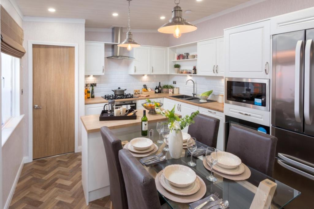 a kitchen with a table with chairs and a refrigerator at Lyndale Lodge in Pulrossie