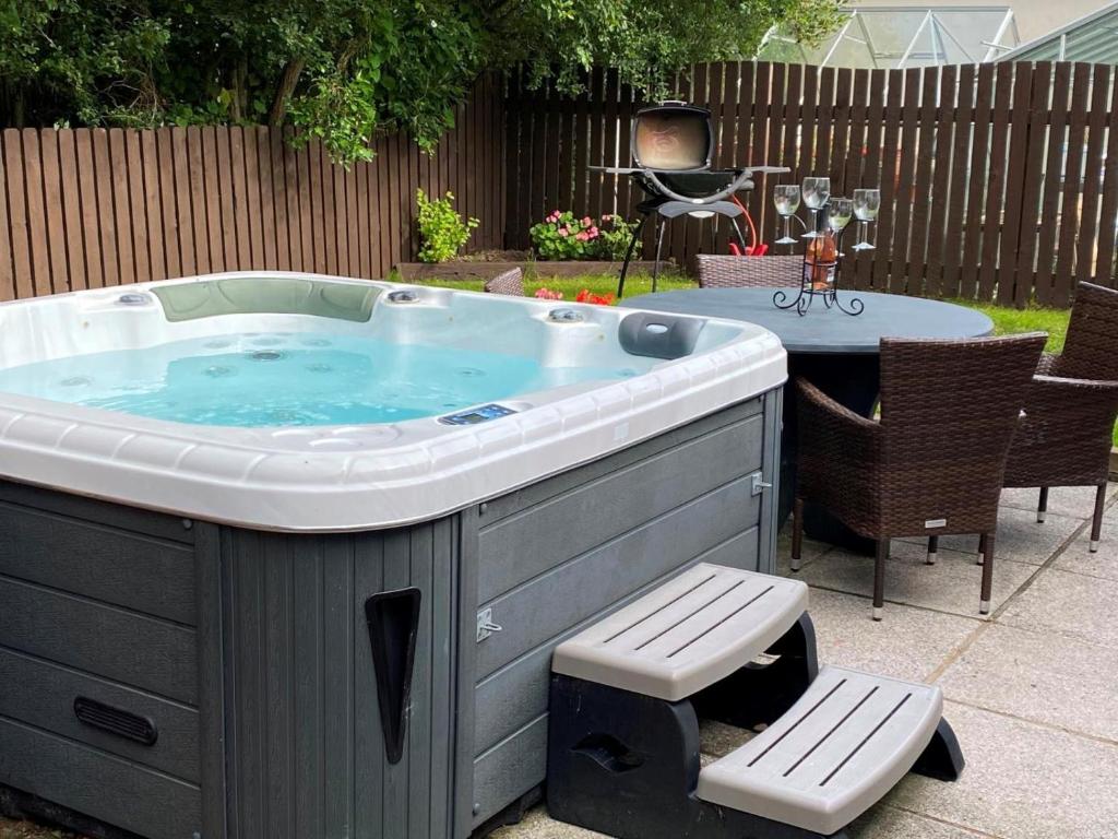 a hot tub in a backyard with a table and chairs at 3 Bed in Bideford oc-89866 in Westward Ho