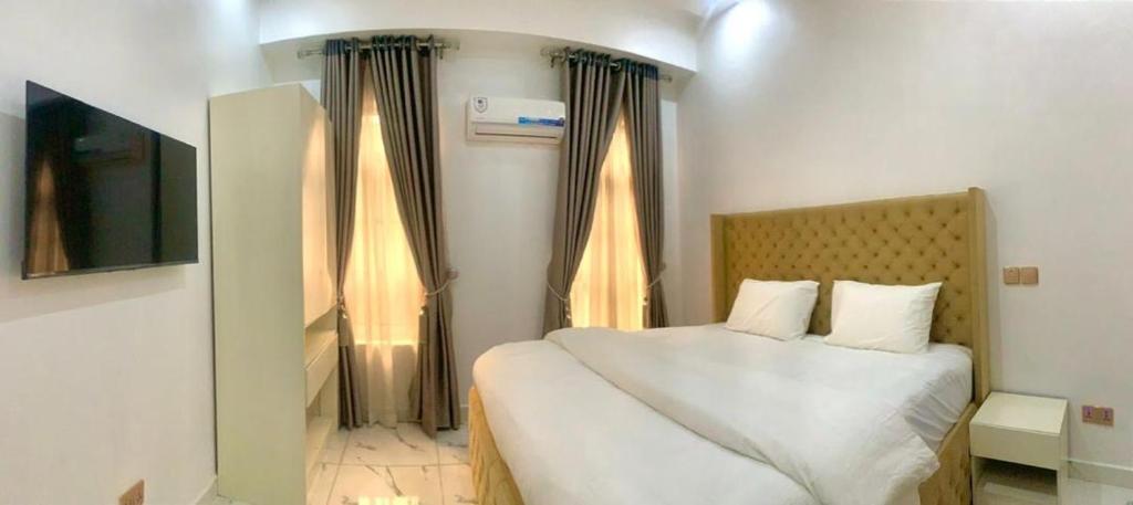 a bedroom with a bed with white sheets and a window at Chris One Bedroom Apartment in Owerri