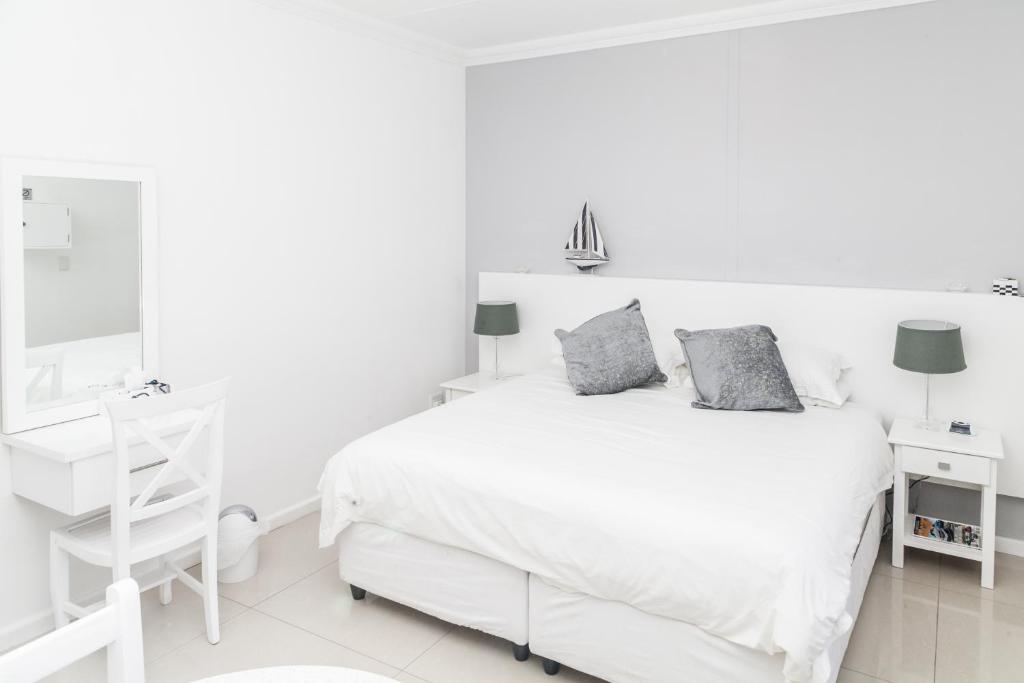 a white bedroom with a white bed and a desk at Studio On Sea in Wilderness