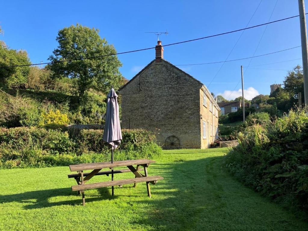 an umbrella sitting on a picnic table in front of a building at 2 Bed in Bridport oc-58848 in Powerstock