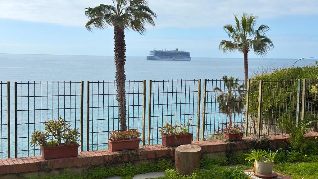 a fence with palm trees and a cruise ship in the ocean at Suite Mazzini 177 - Sanremo in Sanremo