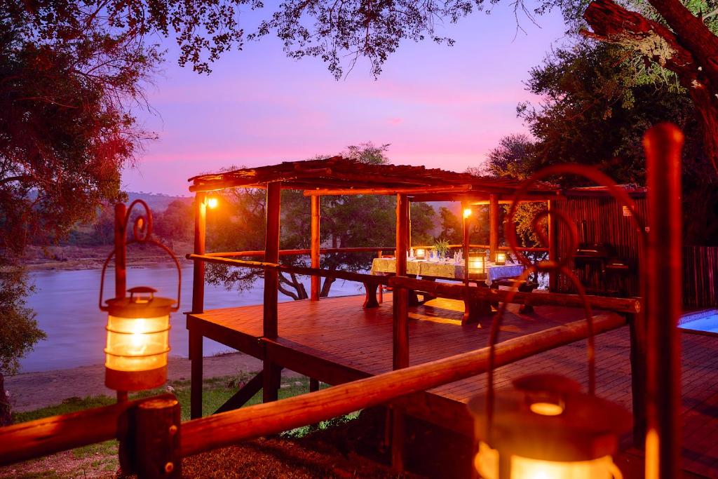 a wooden deck with a gazebo next to a river at Parsons River Camp in Balule Game Reserve