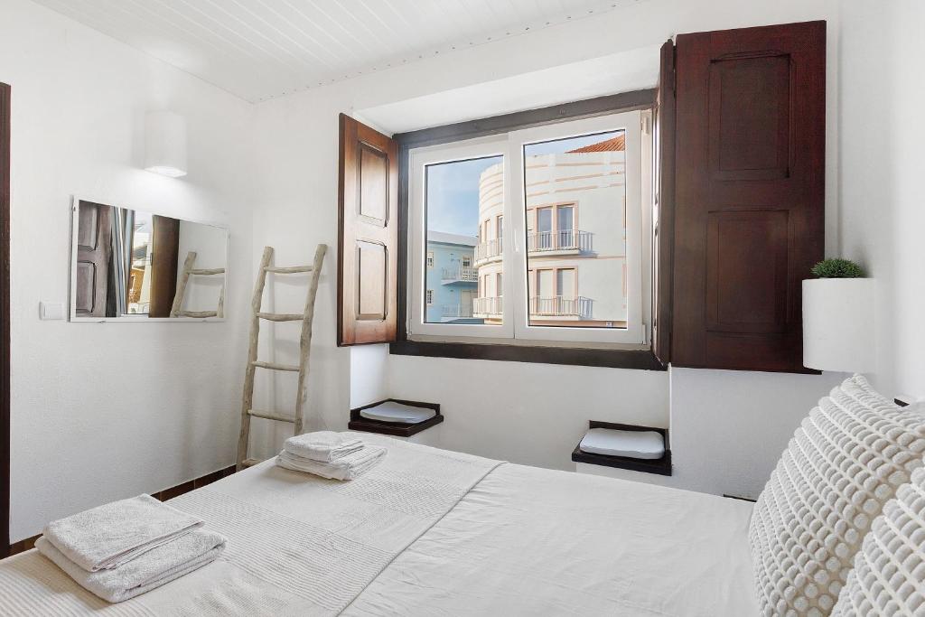 a white bedroom with a bed and a window at Oasis de Ferrel in Ferrel