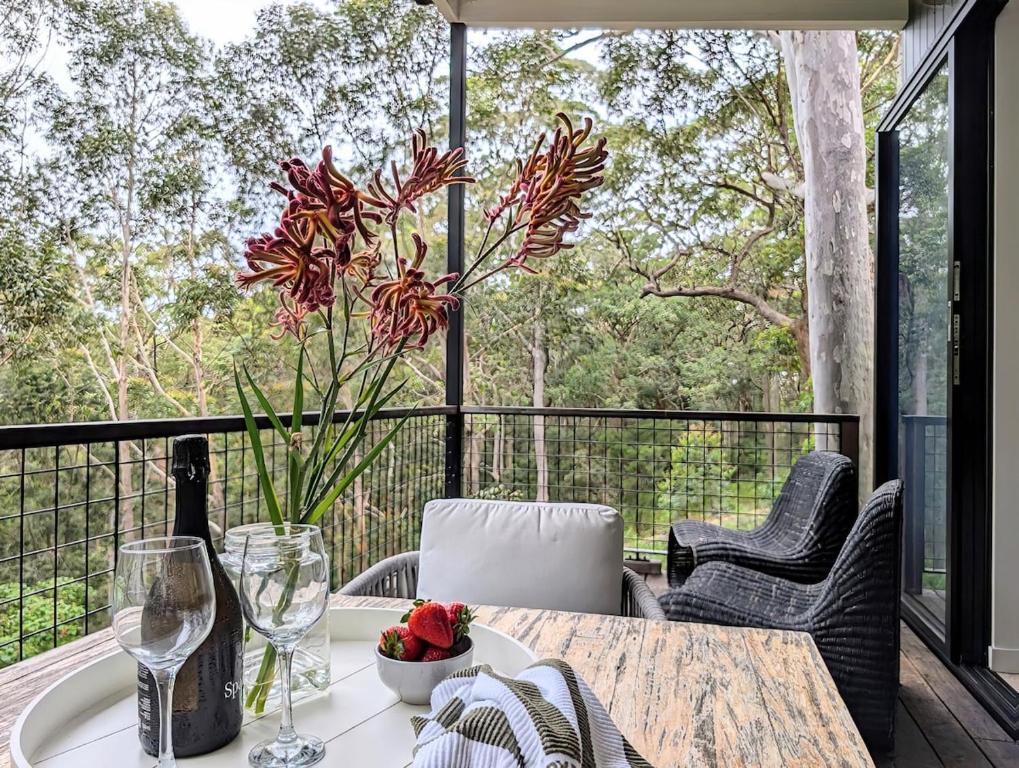 a table with a vase of flowers on a balcony at Stunning Bush Beach House! NEW! in Elizabeth Beach