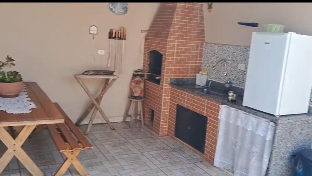 a kitchen with a brick fireplace and a sink at Casa de praia in Peruíbe