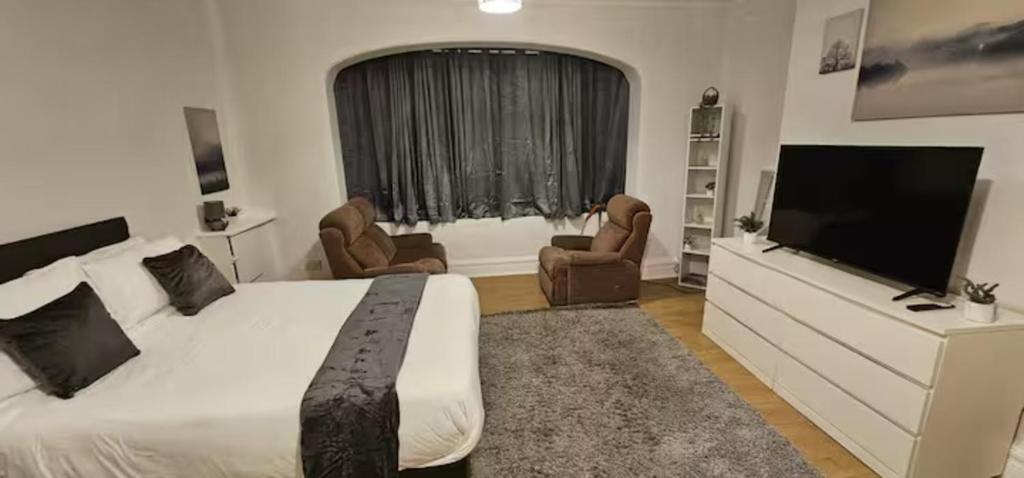 a bedroom with a large bed and a flat screen tv at Spacious Two Bedroom Flat with Dedicated Workspace in Worsley in Worsley