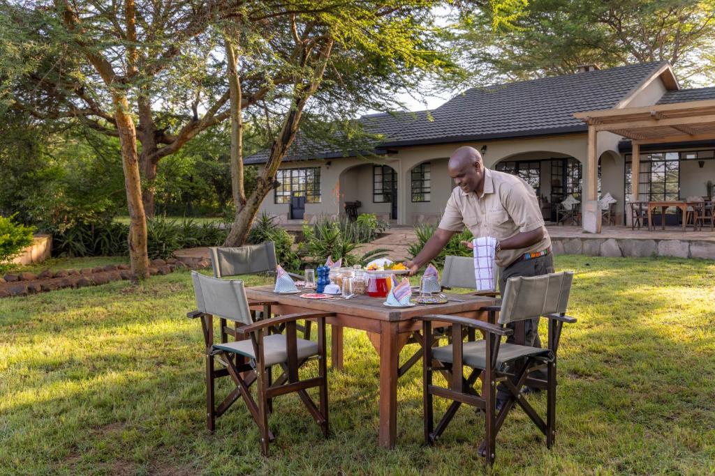 a man standing at a table in a yard at The Maa Guest House in Talek