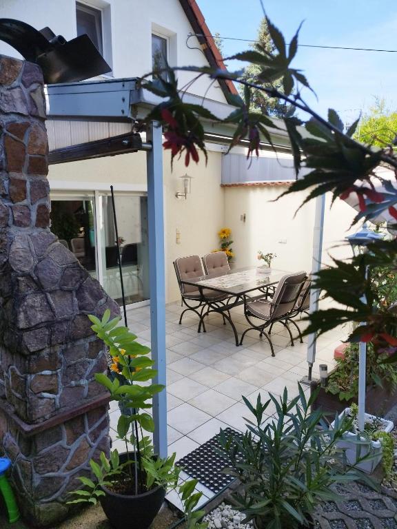 a patio with a table and chairs and a stone wall at "Ferienhaus-Ottendorf" mit Pool und Infarotkabine in Ottendorf