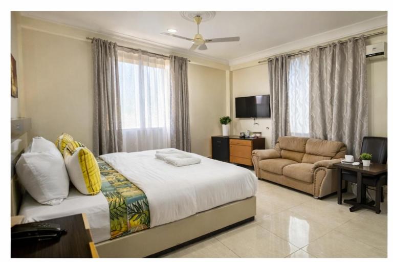a bedroom with a bed and a couch and a television at Covenant Crest Hotel in Accra