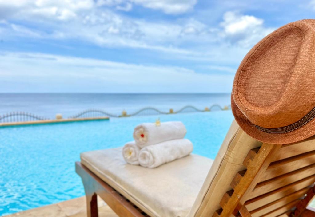 a hat and towels sitting on a chair next to the ocean at Villa Mawar in Pengastulan
