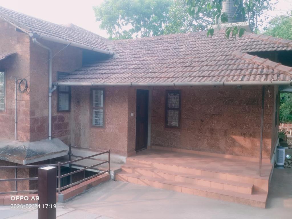 a brick house with a porch and a roof at Nalukettu Veedu in Thottada