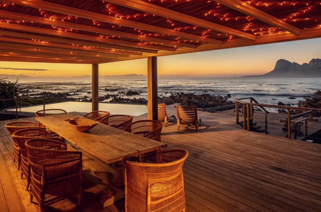 a wooden table on a deck with a view of the ocean at Pringle Bay Villa in Pringle Bay