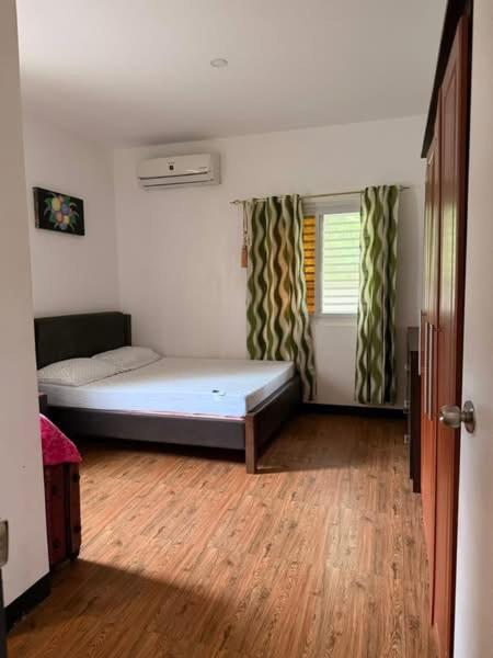 a bedroom with a bed and a wooden floor at Casa Olivia in Puerto Galera