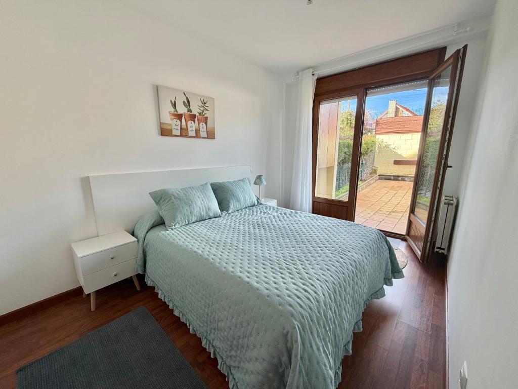 a bedroom with a bed and a door to a patio at Villa de Pedrena - 32801 in Pedreña