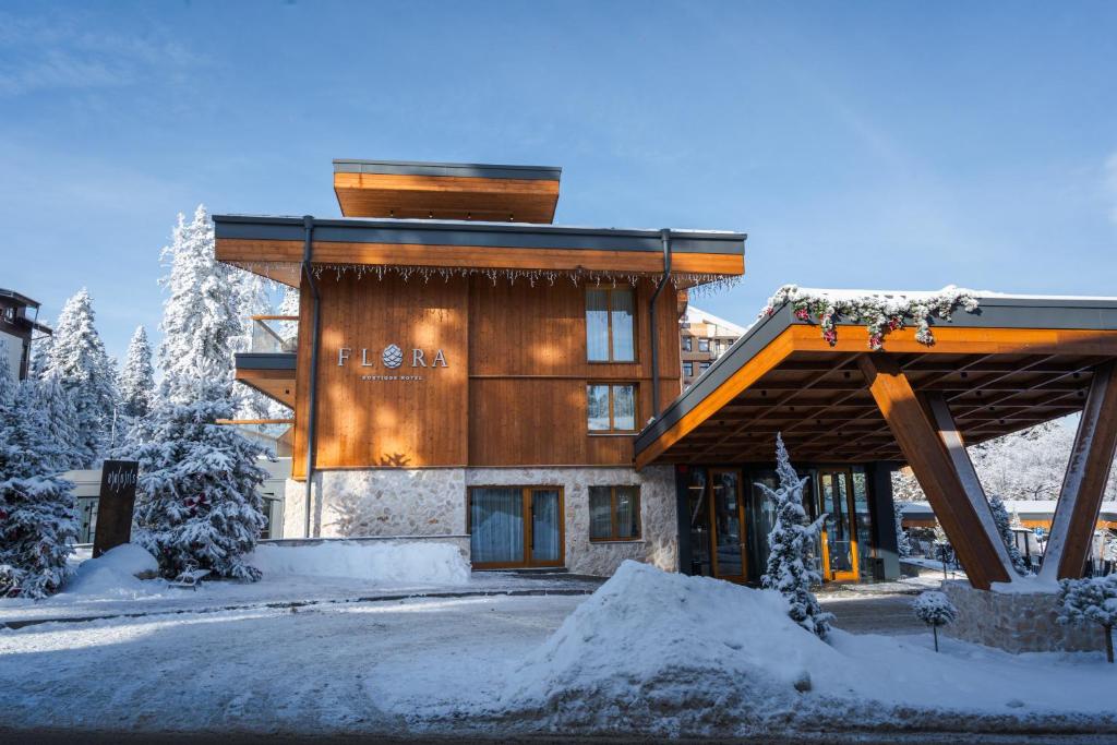 a large wooden building with snow on the ground at Flora Boutique Hotel in Borovets