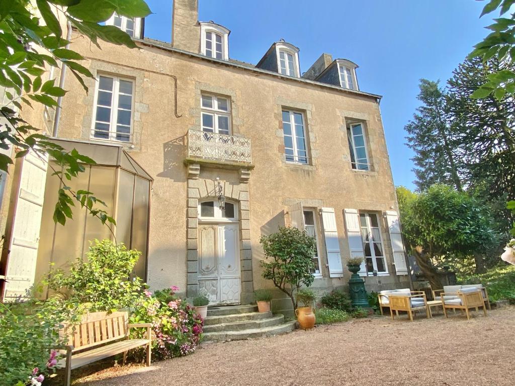 a large brick building with benches in front of it at L'Hotel de Hercé Chambre d'Hote in Mayenne