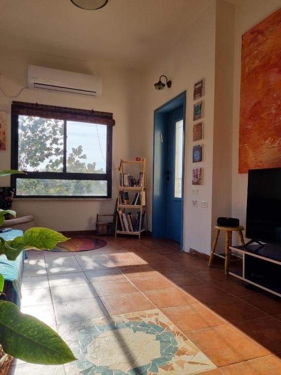 a living room with a large window and a blue door at בין צבעי החול in Sappir
