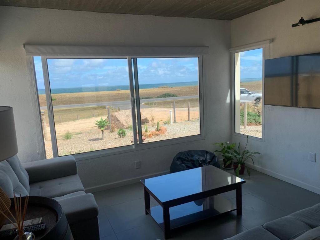 a living room with a couch and a table and two windows at Sur in Barra de Portezuelo