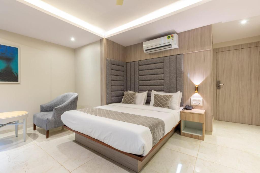 a hotel room with a bed and a chair at Hotel Kurla Suites in Mumbai
