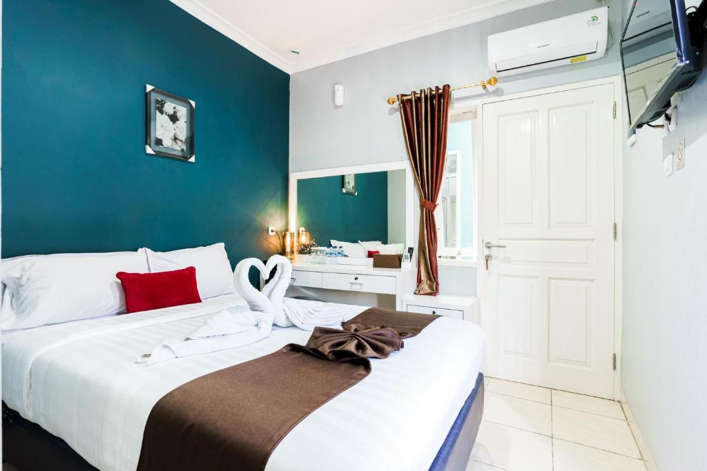 a bedroom with a large bed with a blue wall at Fast Hous Syariah Bogor Mitra RedDoorz in Bogor