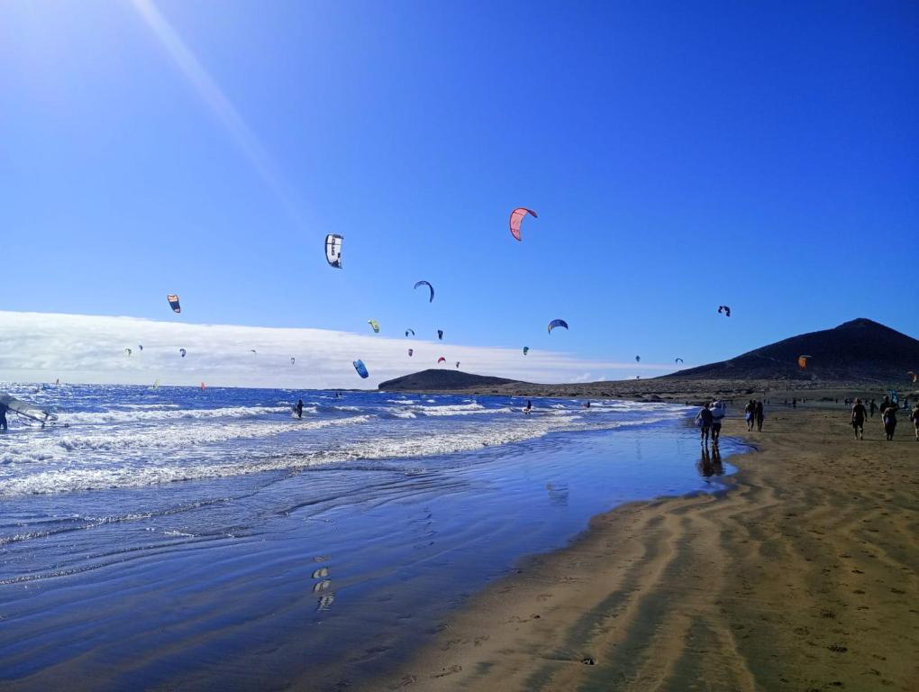 a group of people flying kites on the beach at Medano House Ocean Beach in El Médano
