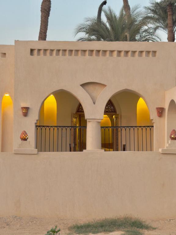 a house with a fence and palm trees at Talia gust house in Al Aqālitah