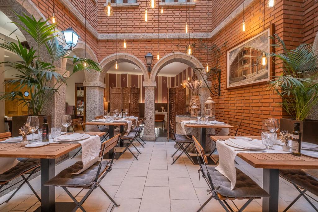 a restaurant with wooden tables and chairs and a brick wall at Casona De Torres in Mondéjar