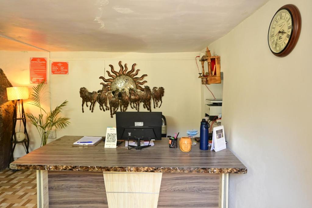 a room with a desk with a computer and a clock at Rudrakshi Inn in Mount Ābu