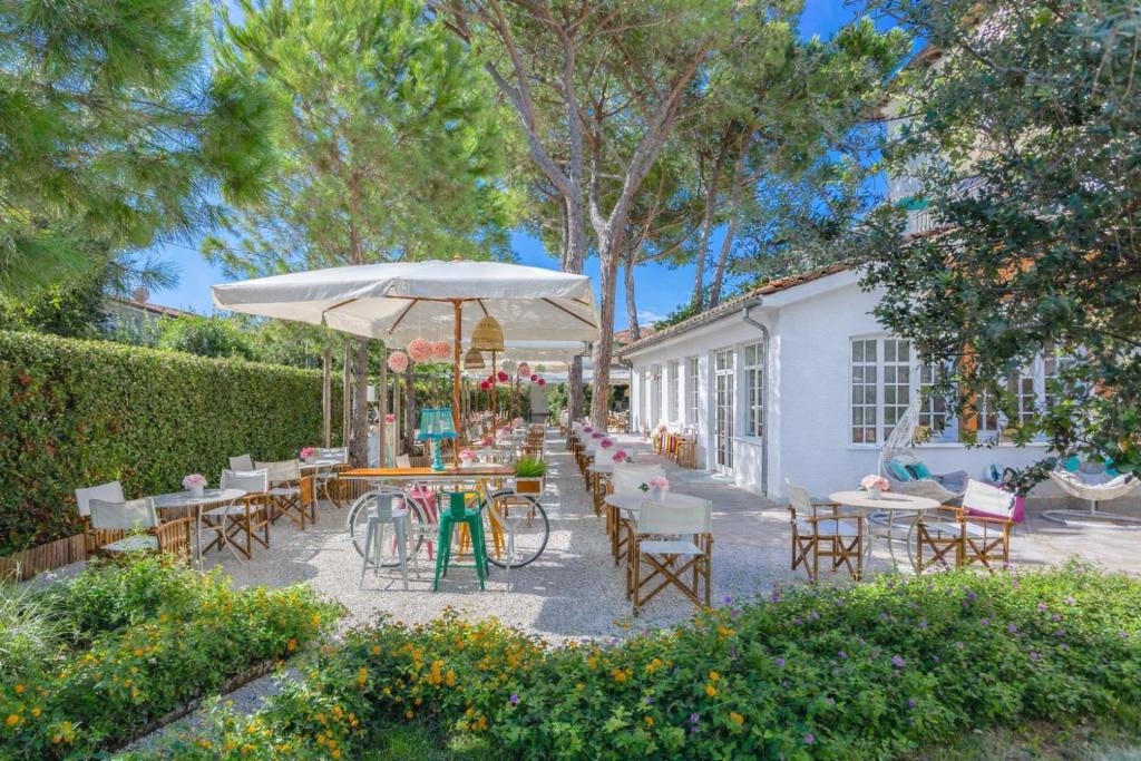 a patio with tables and chairs and an umbrella at Hotel La Pineta Al Mare in Forte dei Marmi