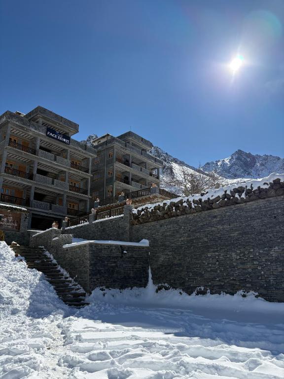 a stone wall in the snow in front of a building at The face resort in Muktināth