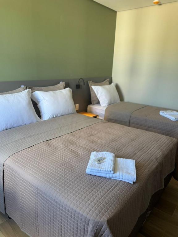 two beds in a room with a towel on the bed at Hotel Maravilha in Caçapava do Sul