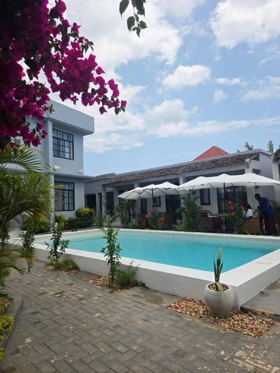 a hotel with a swimming pool in front of a building at Terrys villa pool view room in Kidoti