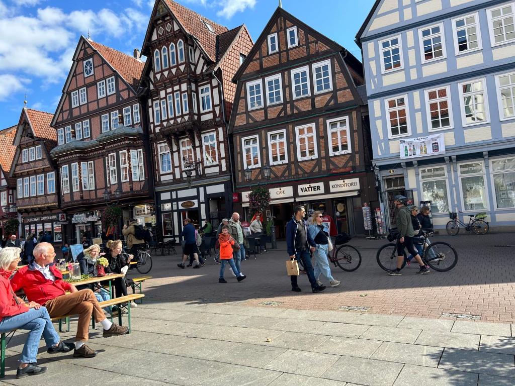 Eine Gruppe von Menschen, die eine Straße mit Gebäuden entlanggehen in der Unterkunft Chez Elly in Celle