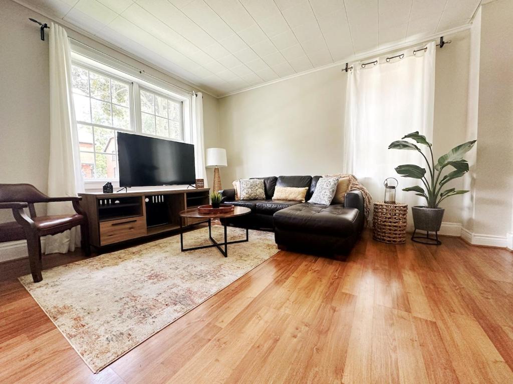 a living room with a leather couch and a flat screen tv at Hidden Gem Steps From River, Restos, Cafés, Parks in Windsor