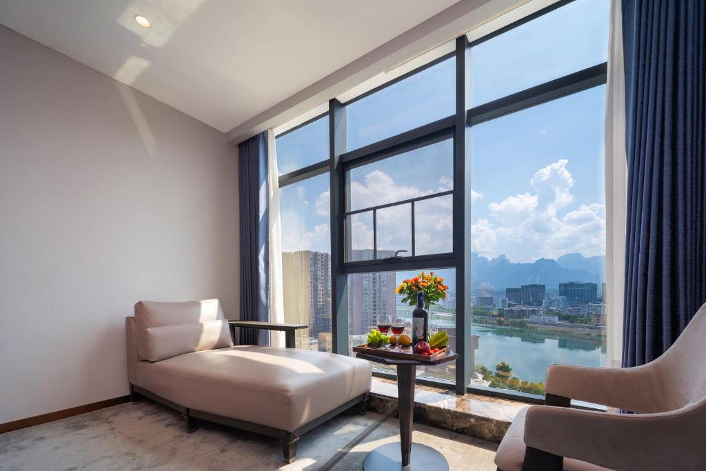 a living room with a chair and a large window at Vanbrugh Bay Hotel - Zhangjiajie Tianmen Mountain in Zhangjiajie