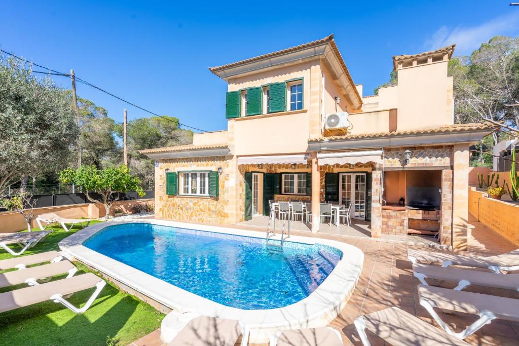 a villa with a swimming pool in front of a house at Villa Trobadors in El Arenal
