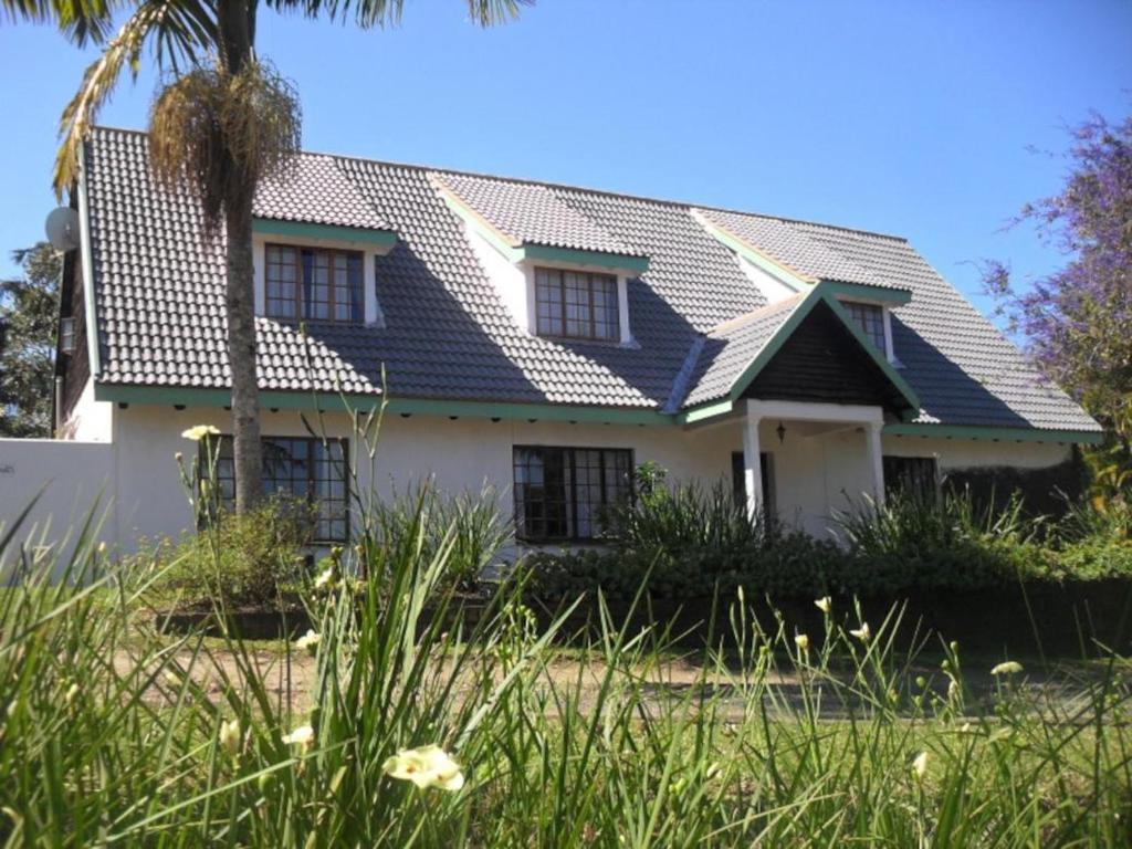 a house with a blue roof on top of it at Bellevue Guest Lodge in Southbroom