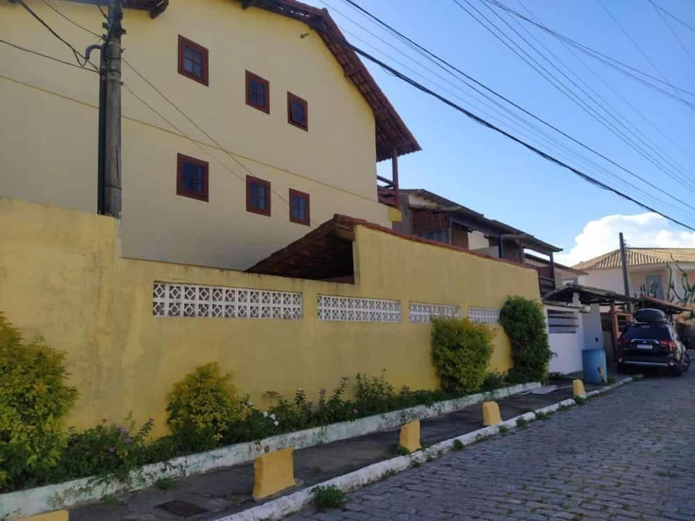 a house with a yellow wall and a street at Duplex 400 meters from Peró Beach in Cabo Frio