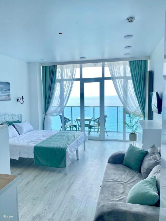 a bedroom with a bed and a couch and a balcony at Batumi in the waves in Batumi
